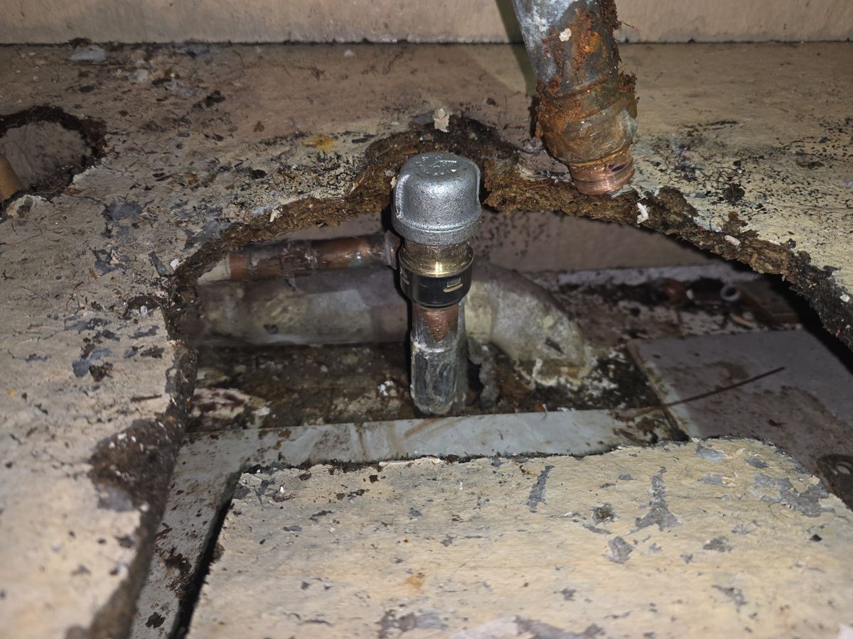 The leak source at the sink drain, with water damage around the pipe.